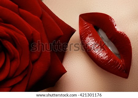 Close-up beautiful female lips with bright red makeup. Perfect clean skin, sexy lip make-up. Beautiful spa portrait with tender red rose flower. Spa and cosmetics