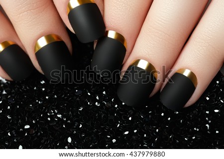 Black matte nail polish. Manicured nail with black matte nail polish. Manicure with dark nailpolish. Golden nail art manicure