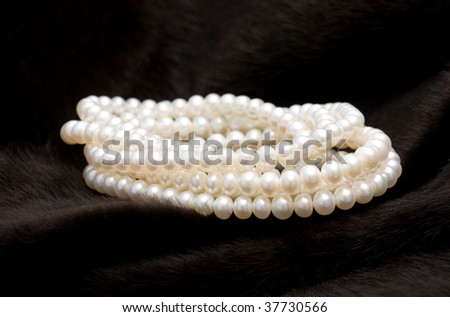 Rolled white pearl string on a black fur background.