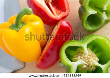 Red, yellow, green bell pepper with knife on cutting board