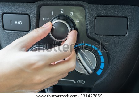 Woman hand turning on car air conditioning system