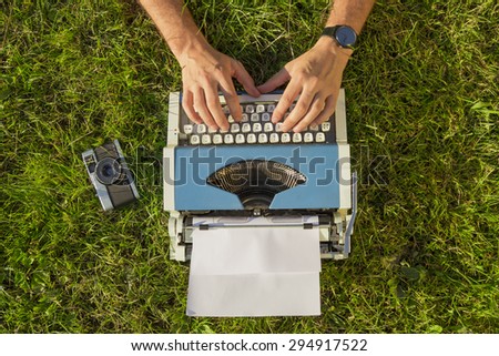 Human hand prints on retro typewriter in the grass