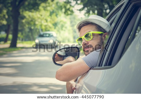 Portrait of young driver wearing sunglasses in driverâ??s seat. Vacation and travel concepts.