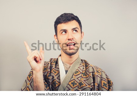 man wearing kimono showing finger above on empty copy space, looking up and said - I have an idea