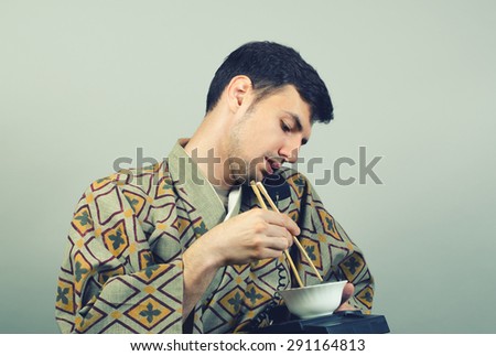 man wearing kimono eating and talking on landline