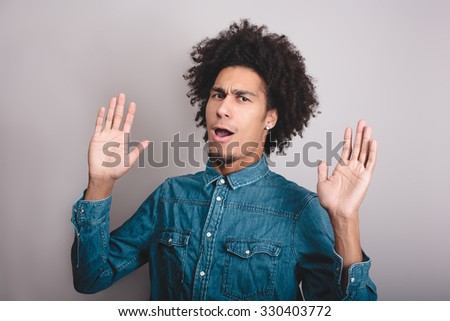 Portrait of a young man with afro asking questions with hands raised