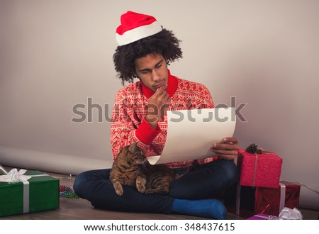 Portrait of young man with afro sitting at his room and preparing Christmas letter or wish list