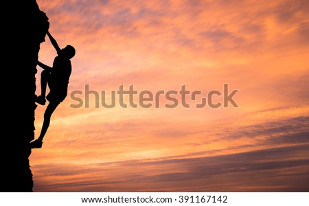A silhouette of man climbing on stone, mountain at sunset.
