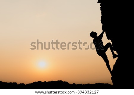 A silhouette of man climbing on stone, mountain at sunset.