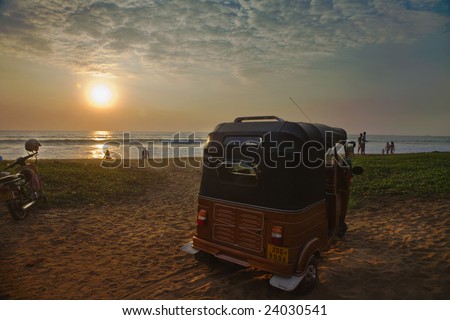 Sri lanka. After day of work fishermen with families have come to bathe on a beach.The three-wheeled car in the foreground is called as tuk-tuk. It is often used as a taxi