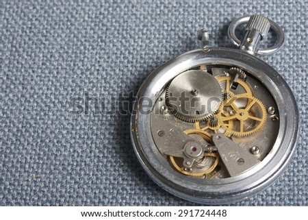 Stopwatch mechanism.The back cover is removed. Inspection prior to repair. Anatomy of time. Disassembled stopwatch on a gray background.