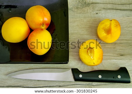 Yellow plums on a black plate and a plum cut in halves