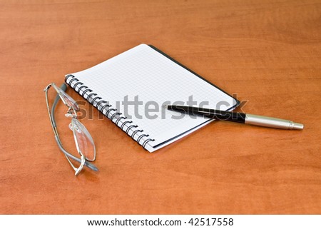 notebook, pen and glasses on desk
