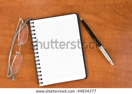 Black pen with notebook and glasses on desk