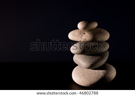 five stones in zen balance over black background