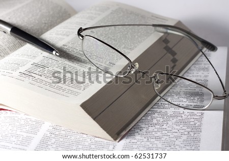 desk with books, glasses and pen