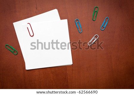 White paper note with a clip over the wooden background