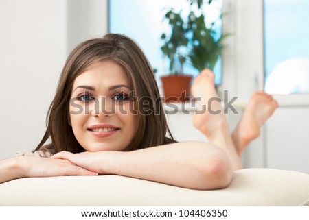 Portrait of woman lying on sofa. Casual style indoor shoot. Happy smiling relaxing girl on living room background.