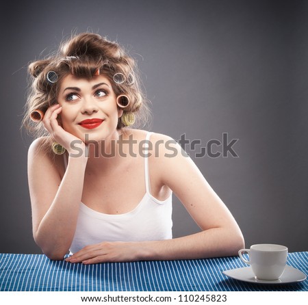 Portrait of a young dreaming woman with long hair on gray background isolated. Smiling and happy girl seat at table