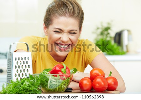 Happy laughing woman cooking vegetables in the kitchen
