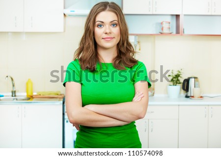 Young woman  standing in the house kitchen. Clothes of green color.