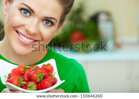 Smiling woman with strawberry. Close up female face  portrait. Healthy mel on a plate.