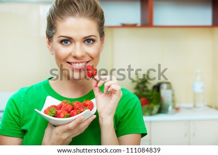 Smiling woman eating strawberry. Close up female face  portrait. Healthy meal on a plate.