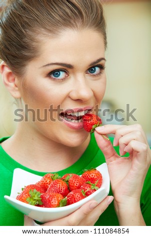 Smiling woman eating strawberry. Close up female face  portrait. Healthy meal on a plate.