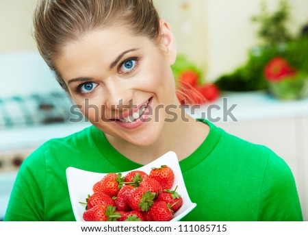 Smiling woman eating strawberry. Close up female face  portrait. Healthy mel on a plate.