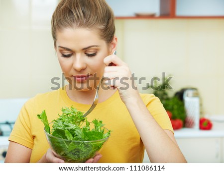 Woman with vegetarian food  standing against  home kitchen interior eating healthy food. Yellow color clothes.
