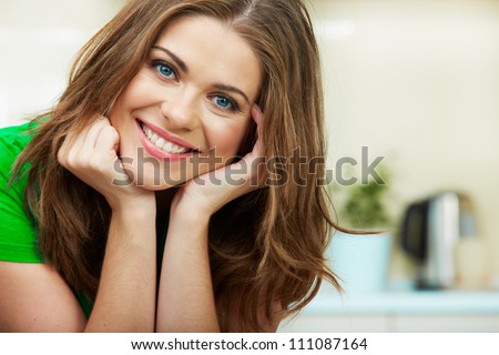 Close up woman face against home kitchen background. Clothes of green color. Portrait of smiling female model.