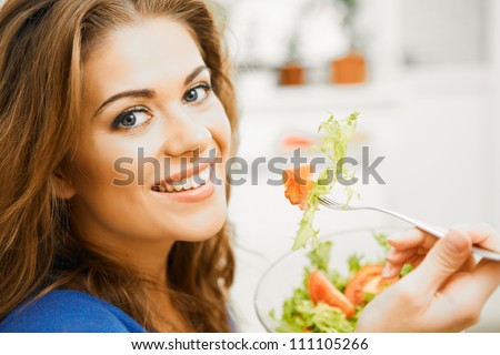 Close up portrait of young woman with long hair sitting  on sofa at home and eating healthy food.