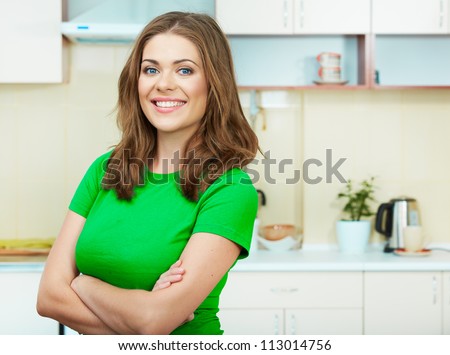Young woman  standing in the house kitchen. Clothes of green color.
