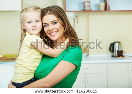 Mother with daughter standing in kitchen. Interior portrait.
