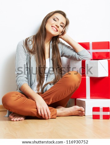 Portrait of a beautiful smiling woman seat on the floor with many christmas gift against white wall background.