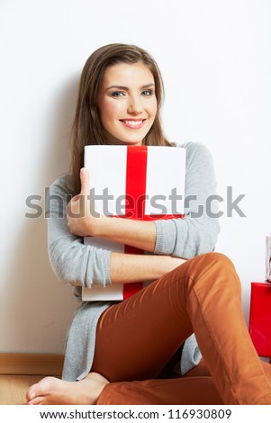 Portrait of a beautiful smiling woman seat on the floor with many christmas gift against white wall background.