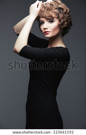 Fashion Style Woman with curly  hair on gray  background isolated  portrait. Young model posing in studio.