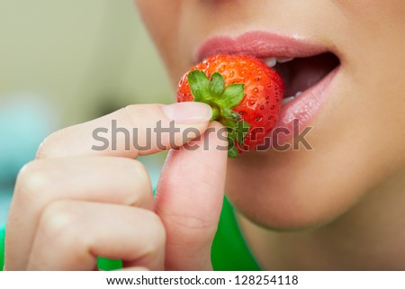 Lips, fingers and strawberry close up.