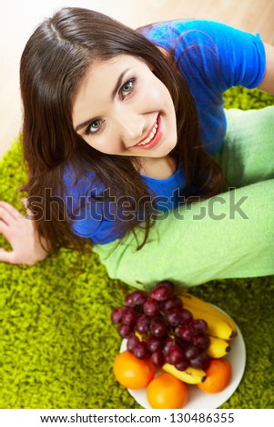 Woman seating on floor with fruits. Female model indoor portrait.