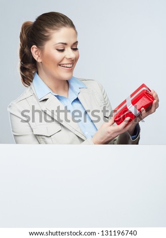 Corporate bonus concept . Smile Business woman hold red gift box, portrait with blank white board on gray isolated . Female smiling model .