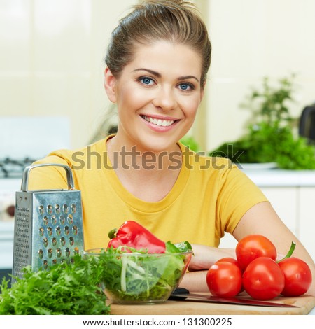 Happy Woman prepare  vegetarian food,  standing against  home kitchen interior background. Yellow color clothes. Woman Face close up portrait.
