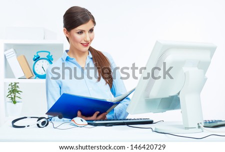 Portrait of young business woman working with paper at computer in white office. Smiling female model posing in office.
