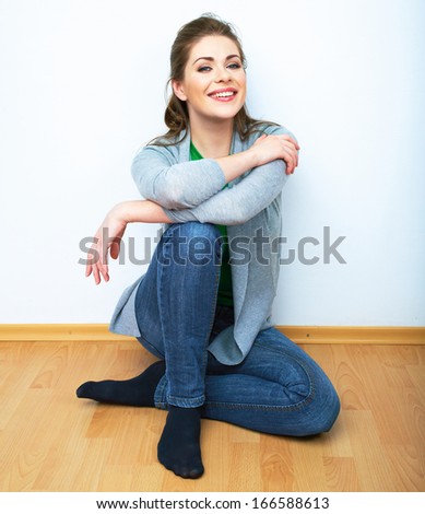 Woman natural portrait. Smiling girl seat on a floor. White background isolated.