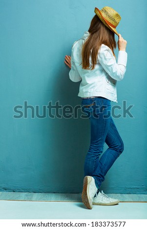 Fashion model standing back against blue.
