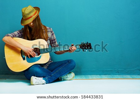 Girl fashion portrait. Model play guitar. Blue background.