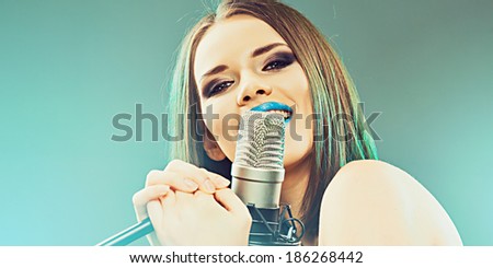 Girl singing into a microphone. Studio sound records.