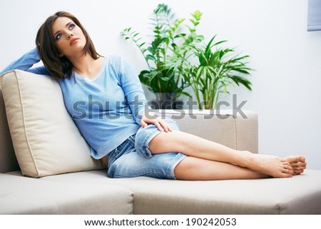 Portrait of young woman sitting on couch at home. Relaxing girl.