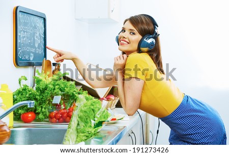 Woman in kitchen show on menu board. Cooking fun with music.