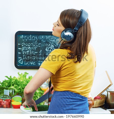 Woman standing back in kitchen, cooking healthy food with fun and listen music with headphones.