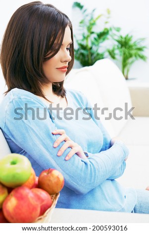 Beautiful woman sitting on sofa with apples.